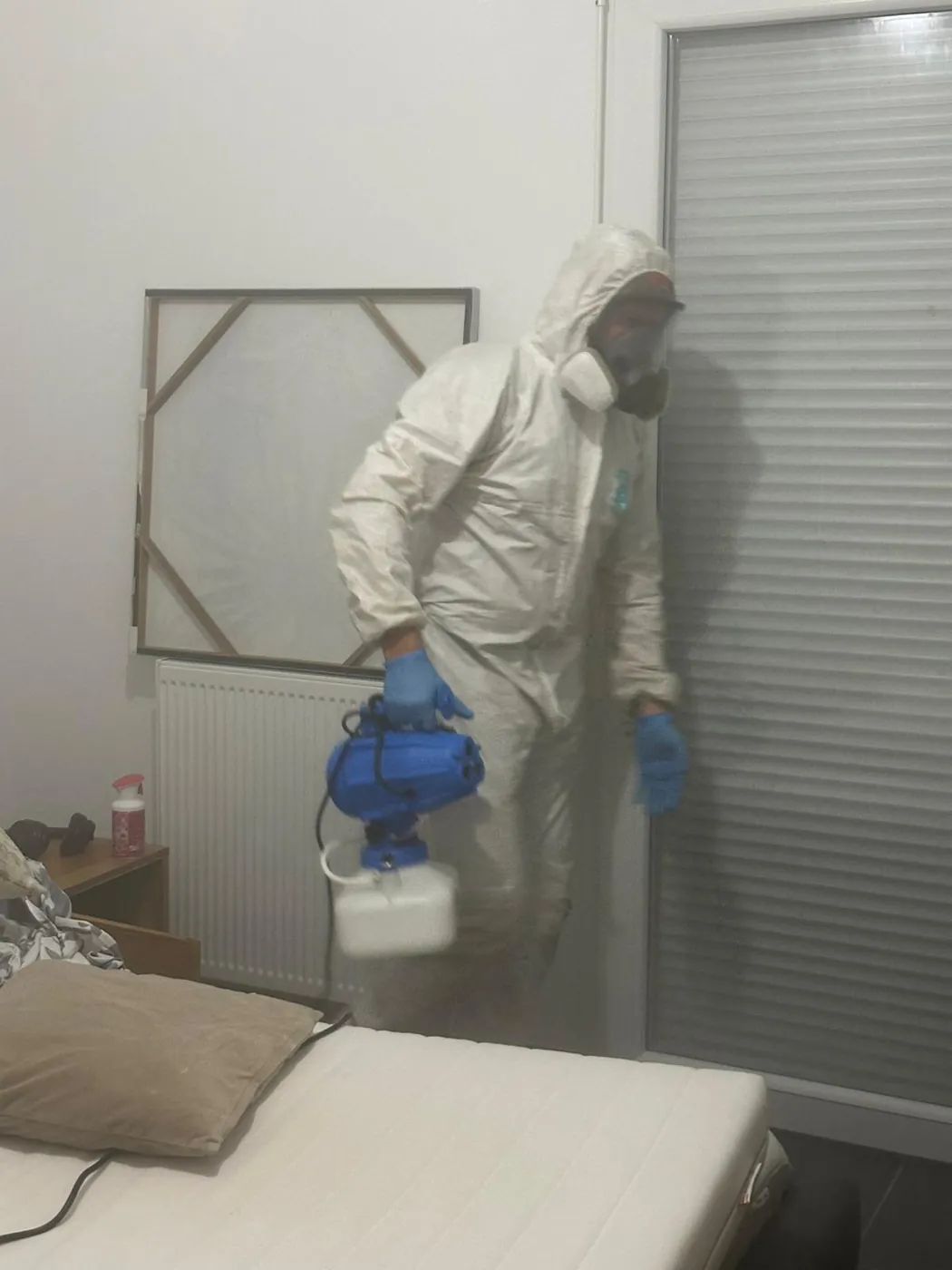 Technicien en tenue de protection traitant une chambre contre les punaises de lit à Aix-en-Provence